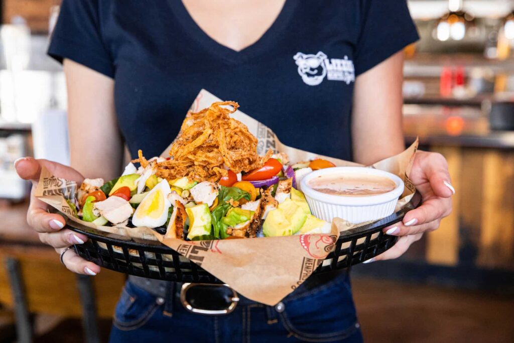 Server carrying a basket of Lizzie’s House Salad