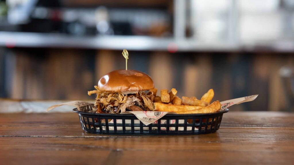 Lizzie's Smokehouse Cheeseburger topped with pulled pork, brisket, and fried onions with a side of fries