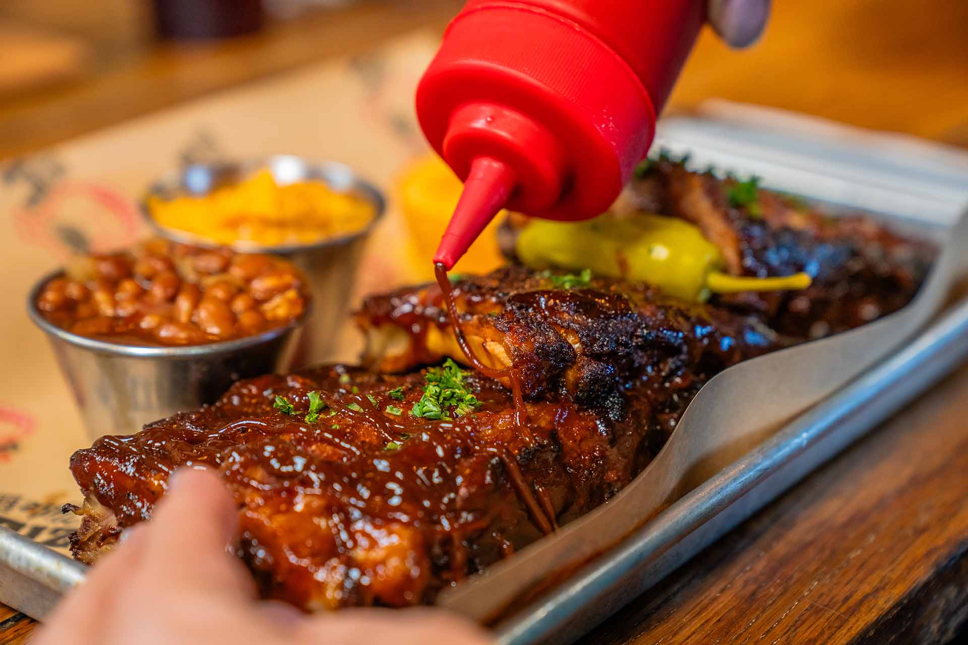 Closeup of BBQ sauce being added to rack of ribs at Lizzie's Memphis Style BBQ